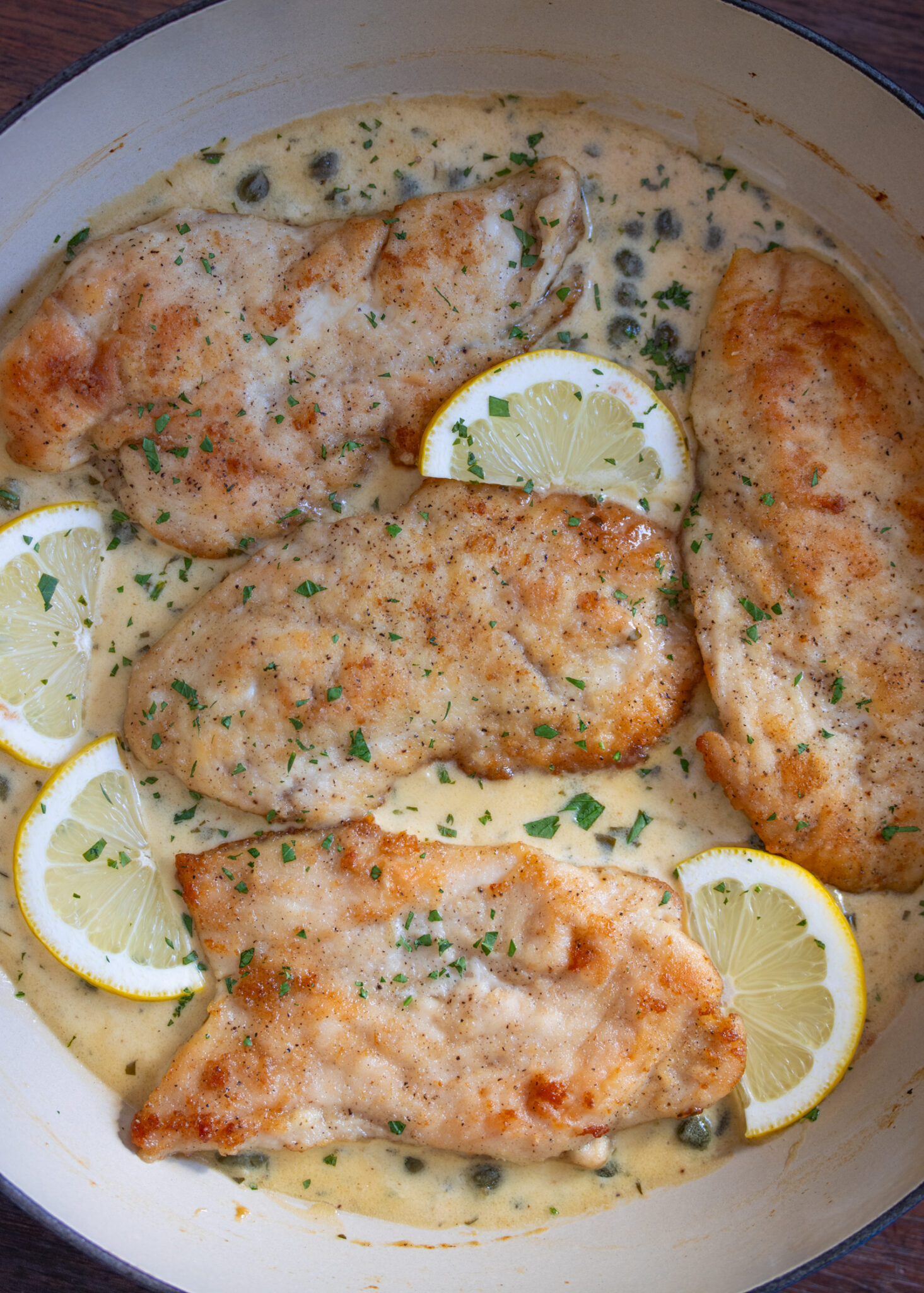 Close up view of the chicken in the pan with lemon slices. 