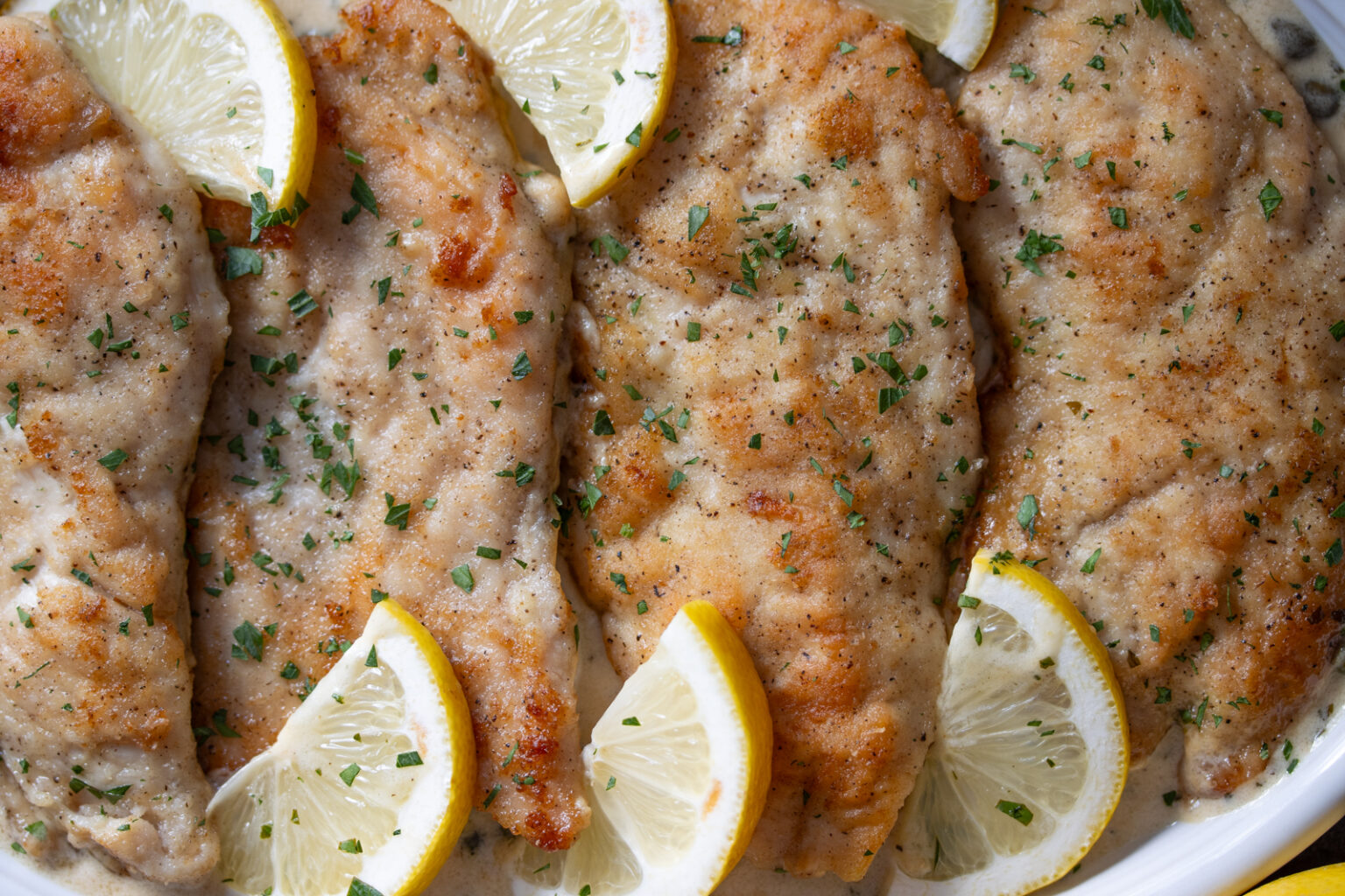 A close up view of the picatta served with lemon slices. 