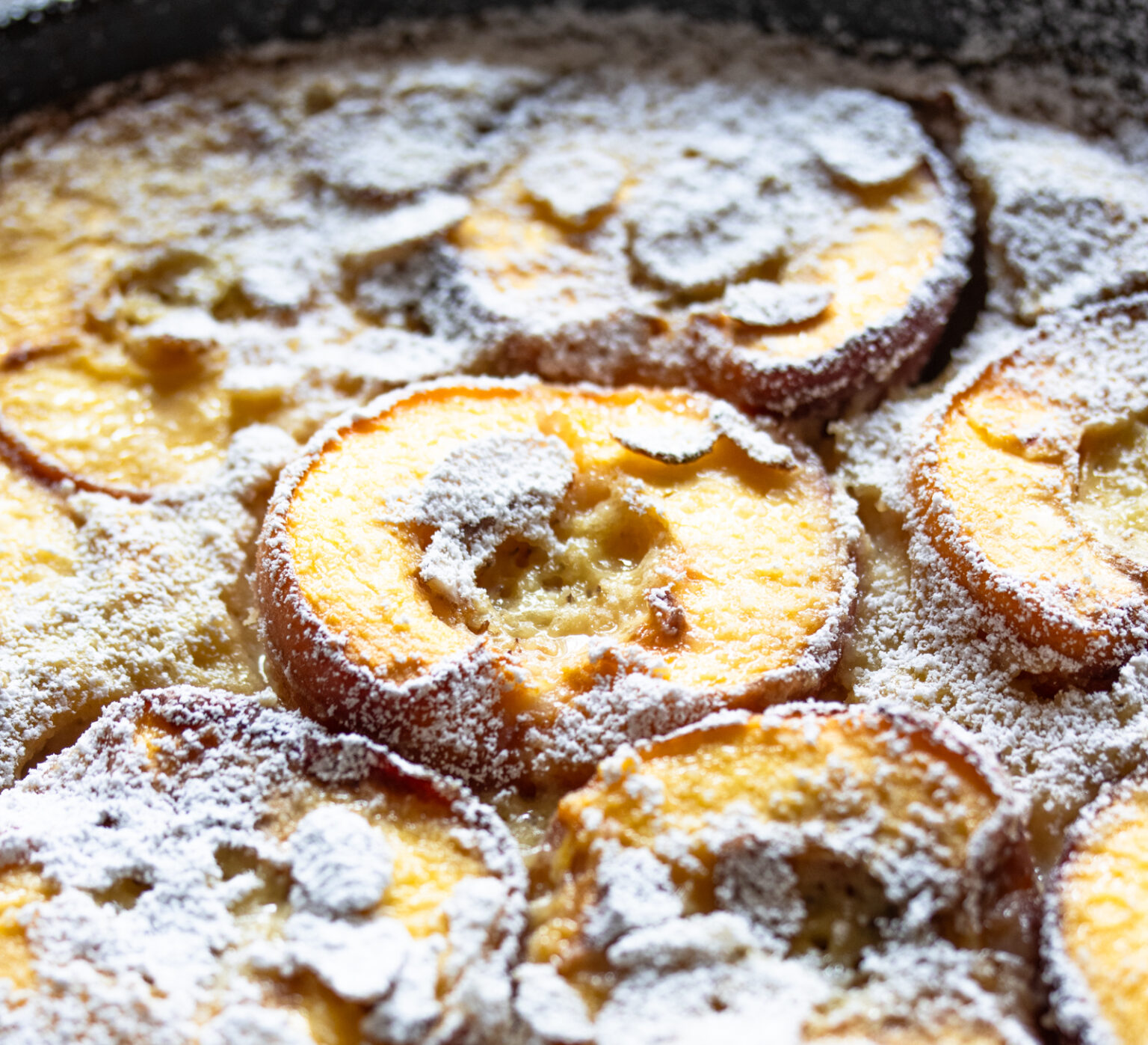 Peach clafoutis close up with dusting of sugar over it.