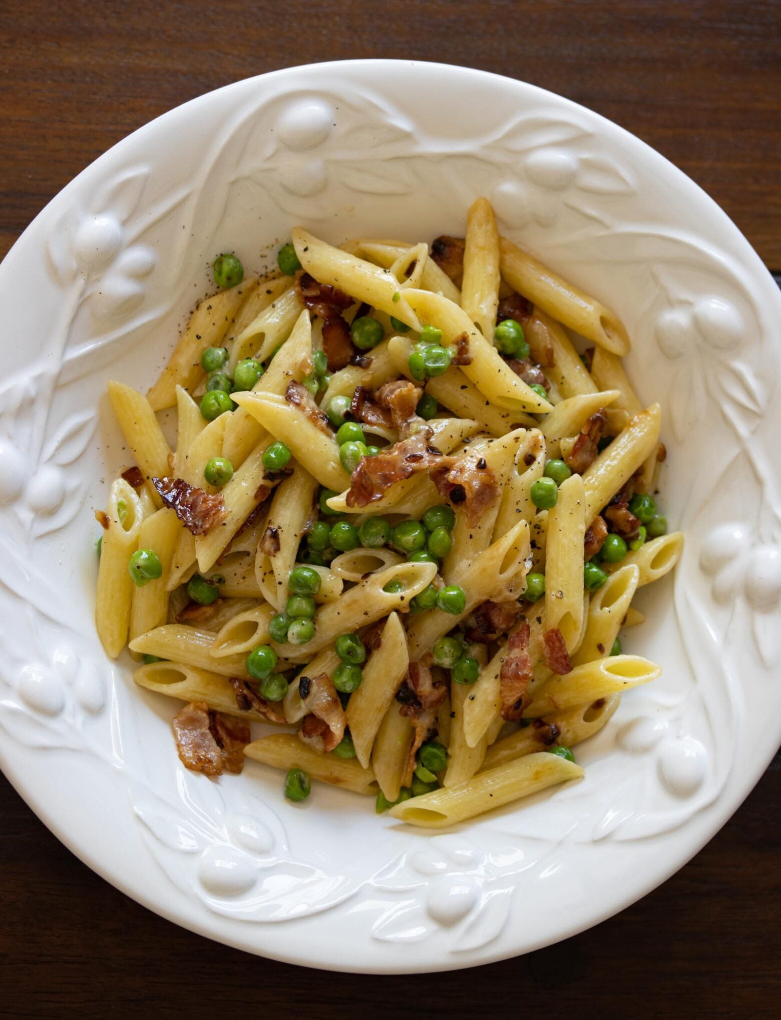 Penne pasta, Peas and bacon in a white serving dish.