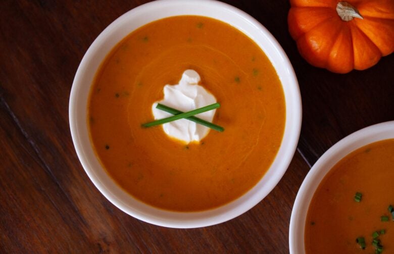 pumpkin ginger soup in white bowl with chives as a garnish