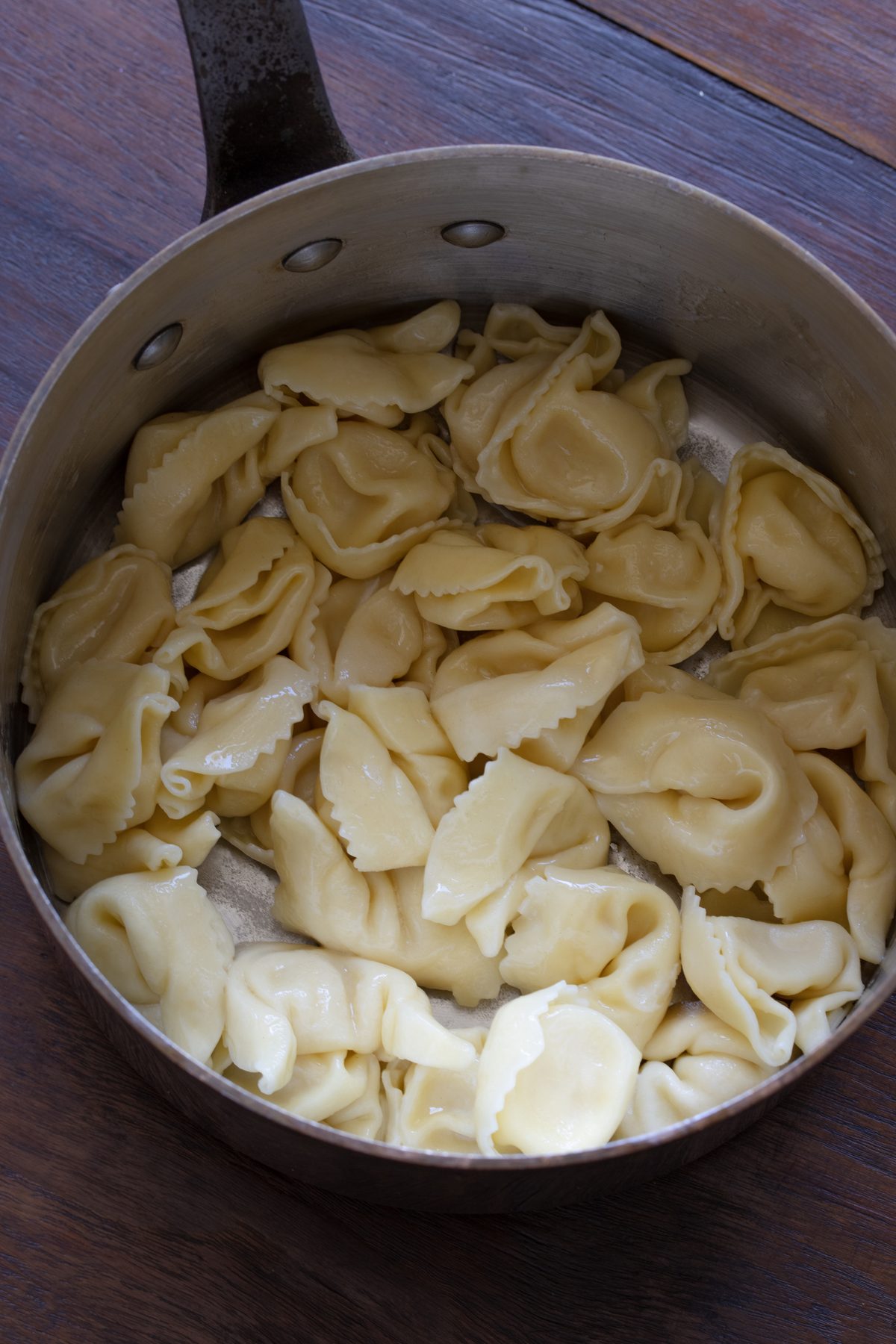 Return the drained tortellini back to the cooking pot and added butter to them.