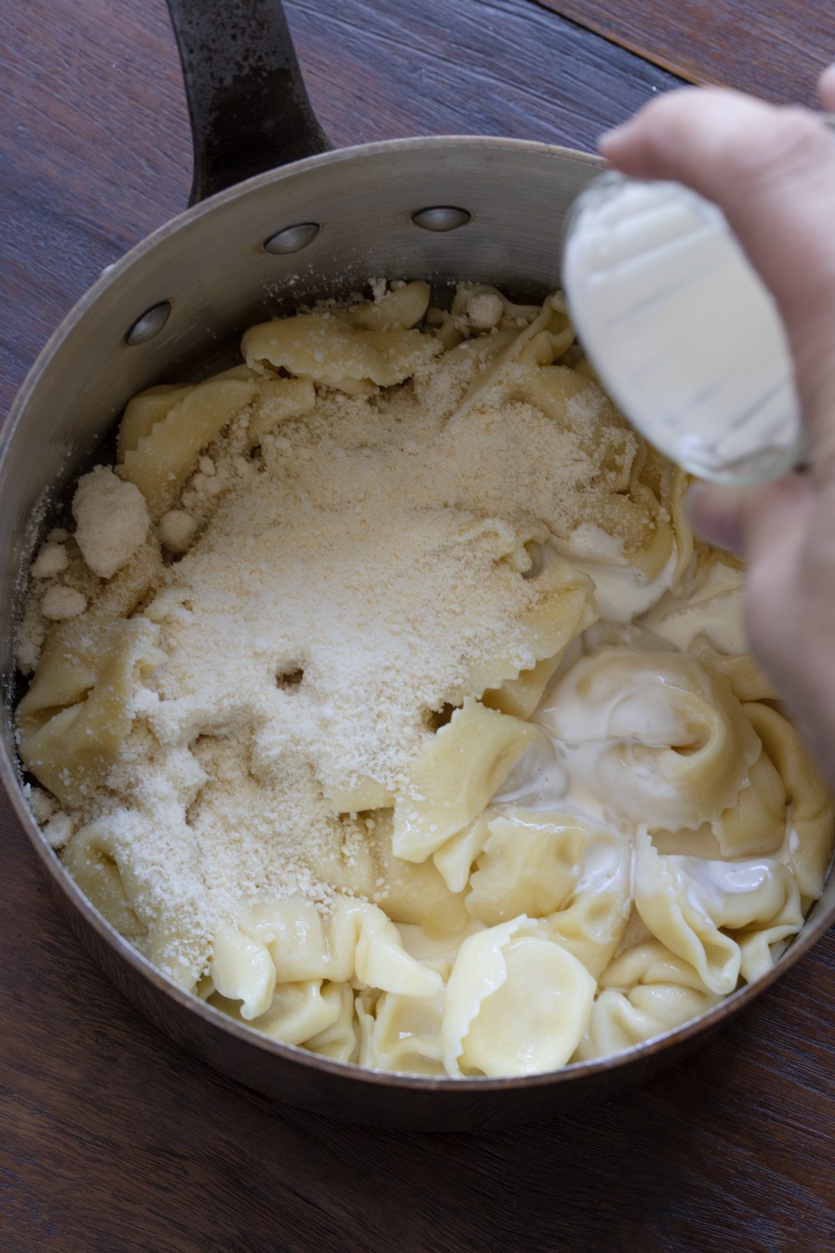Heavy cream added to the cheese and tortellini in the pot.