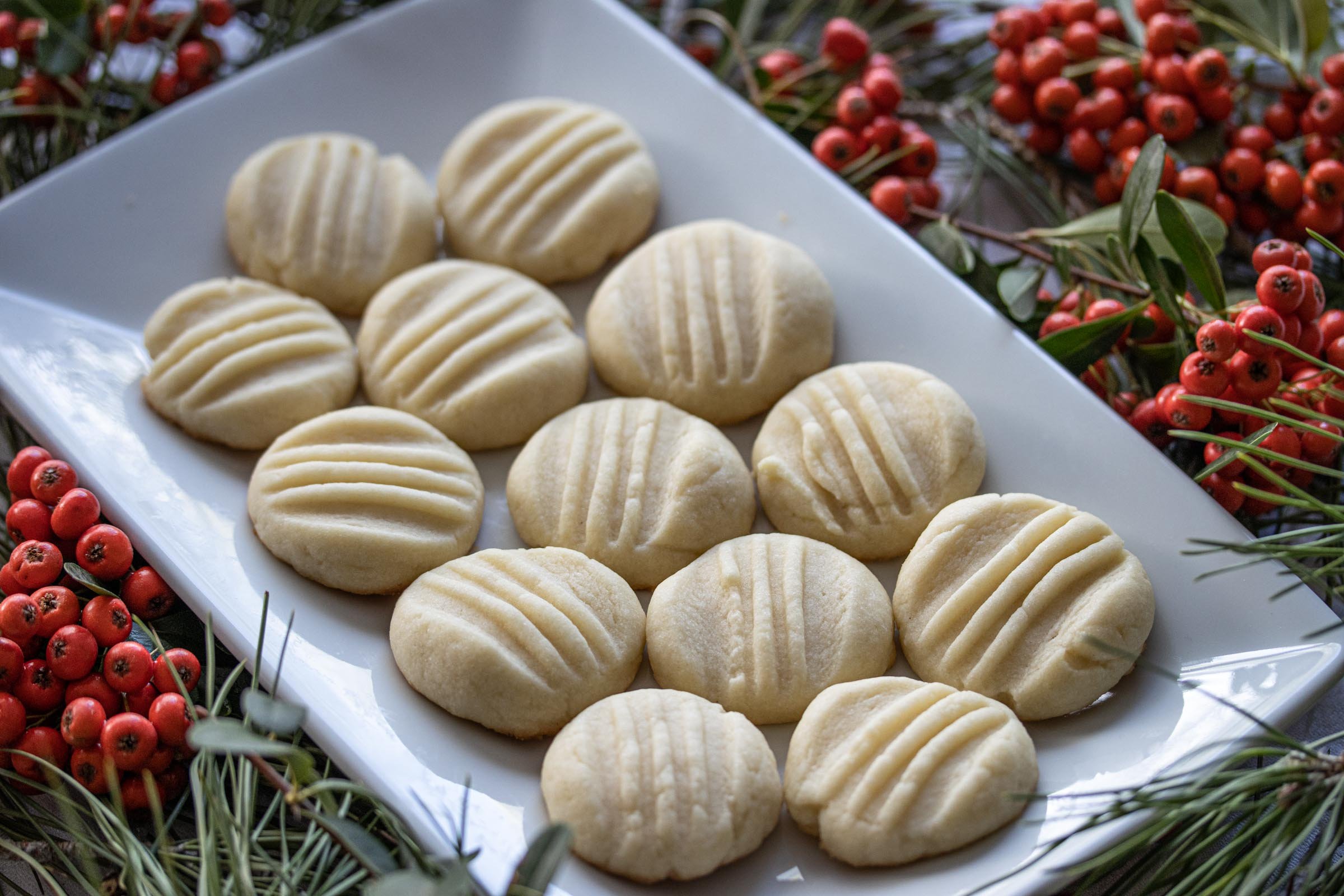butter cookies in a white plate surrounded by holly