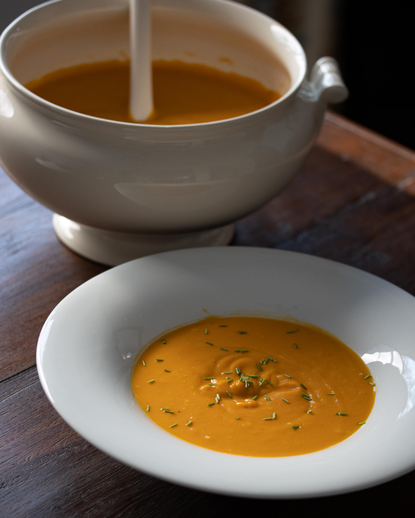 Easy cream of carrot soup inside a soup terrine and served in a white dish