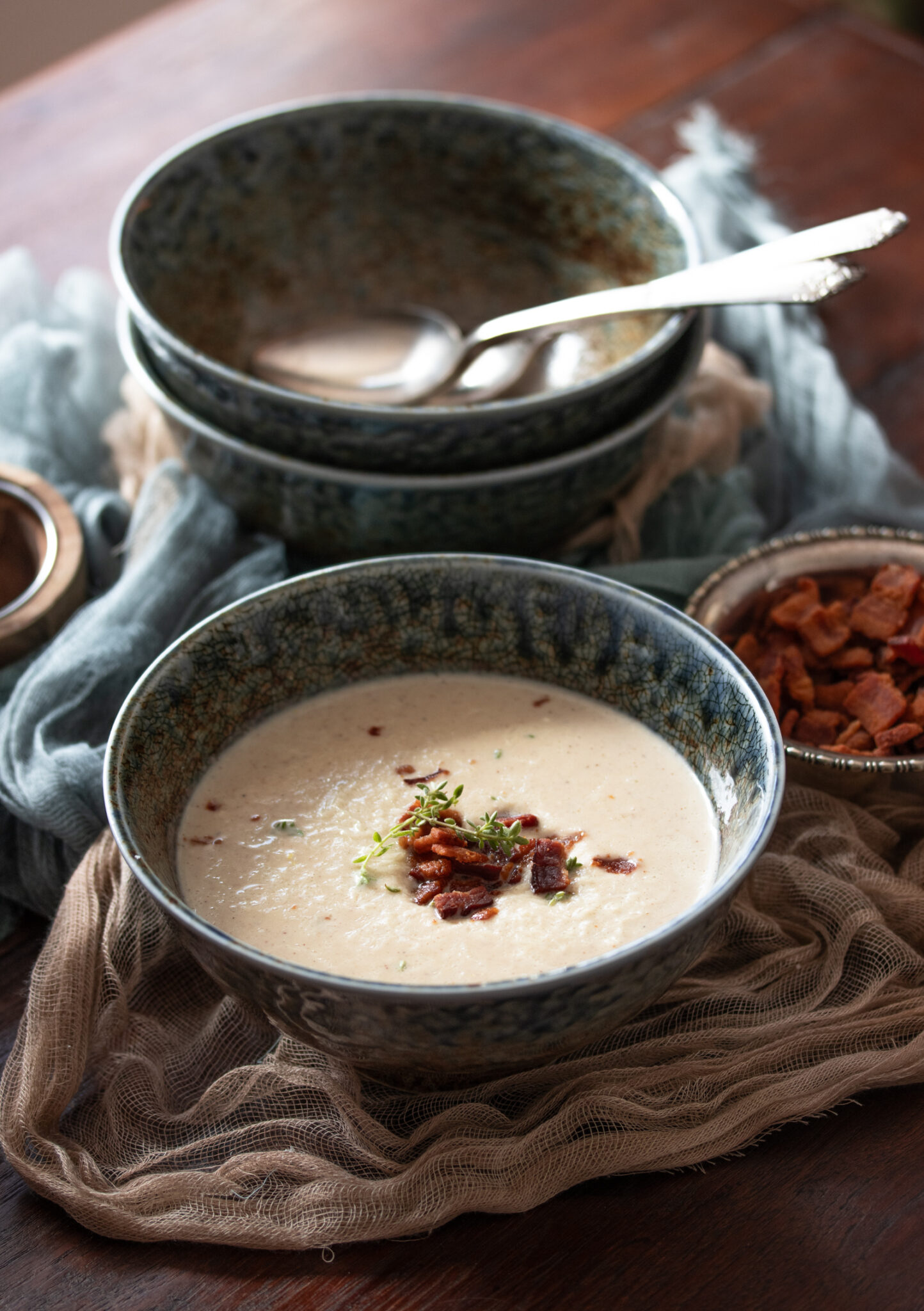 roasted cauliflower soup Roasted Cauliflower Soup in a blue bowl with bacon bits next to it