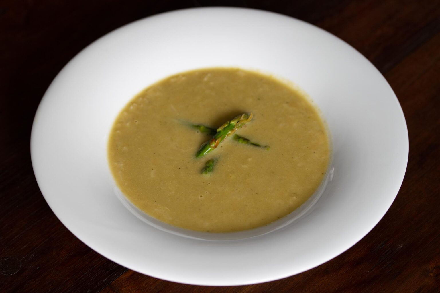 asparagus soup with caramelized leeks served on a white plate