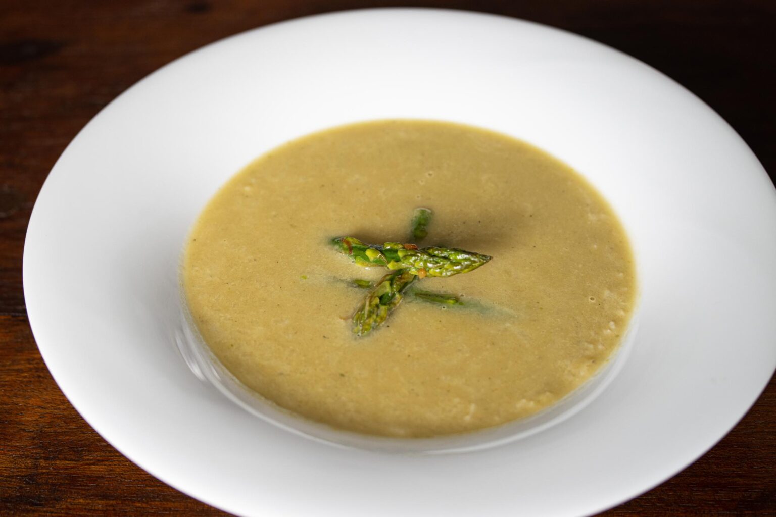 asparagus soup with caramelized leeks served on a white plate