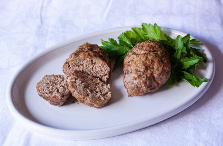 individual meatloafs in a white plate over a white tablecloth
