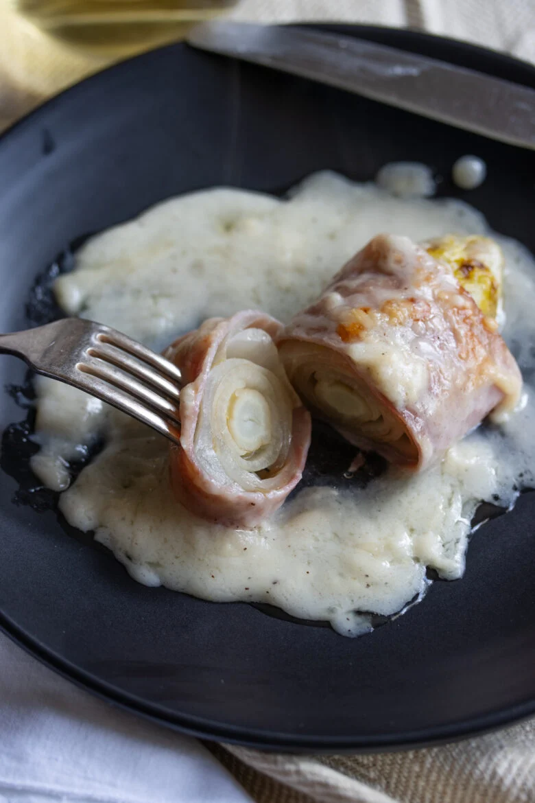 Endive Ham Gratin in a black plate with fork and cut