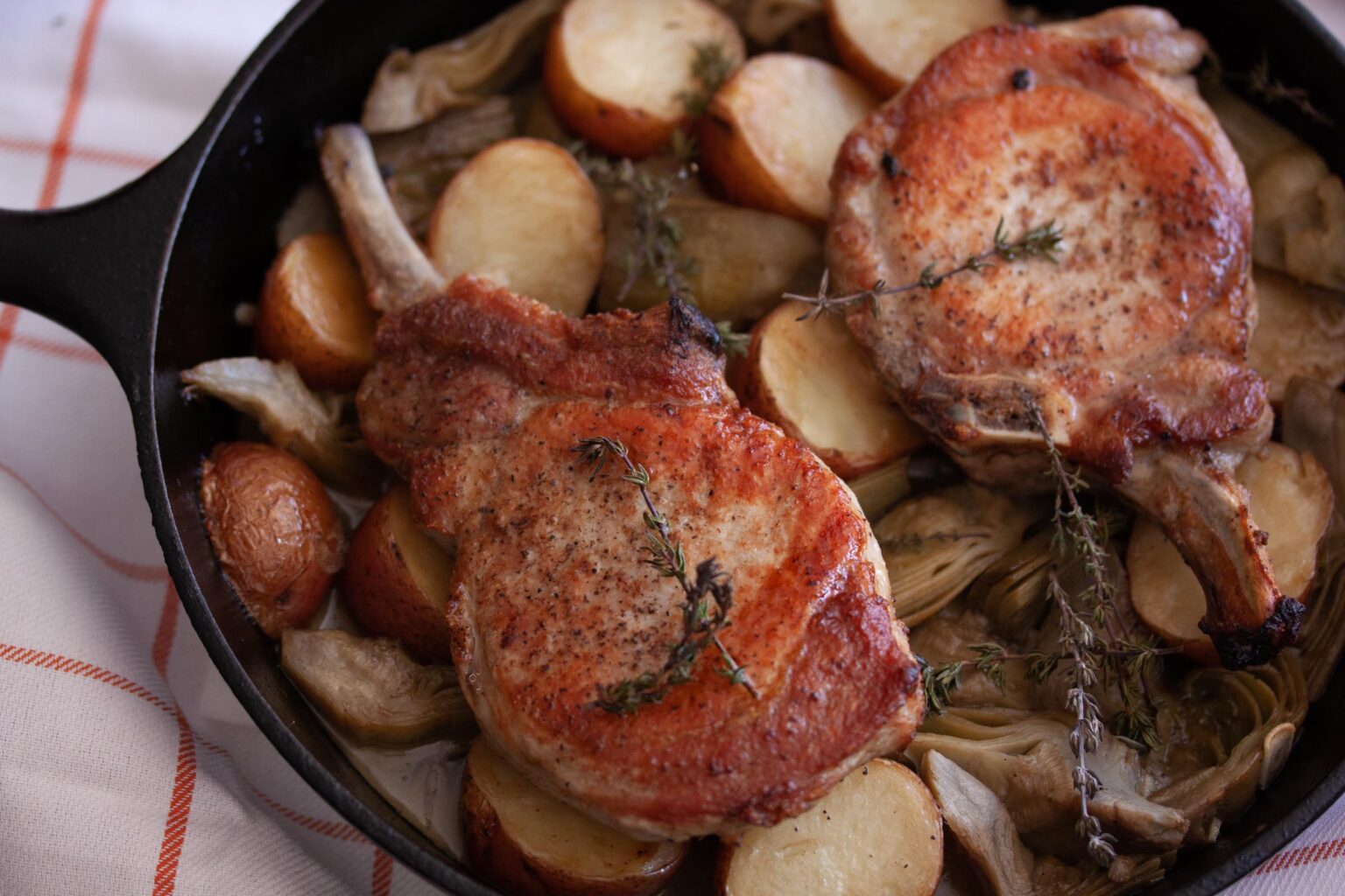 Roast pork chops with artichokes and potatoes done and served in the skillet.
