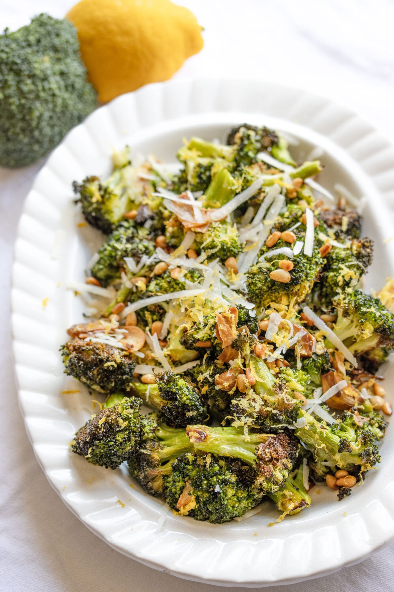 oven roasted broccoli with lemon and garlic served in a rectangular white scalloped dish.