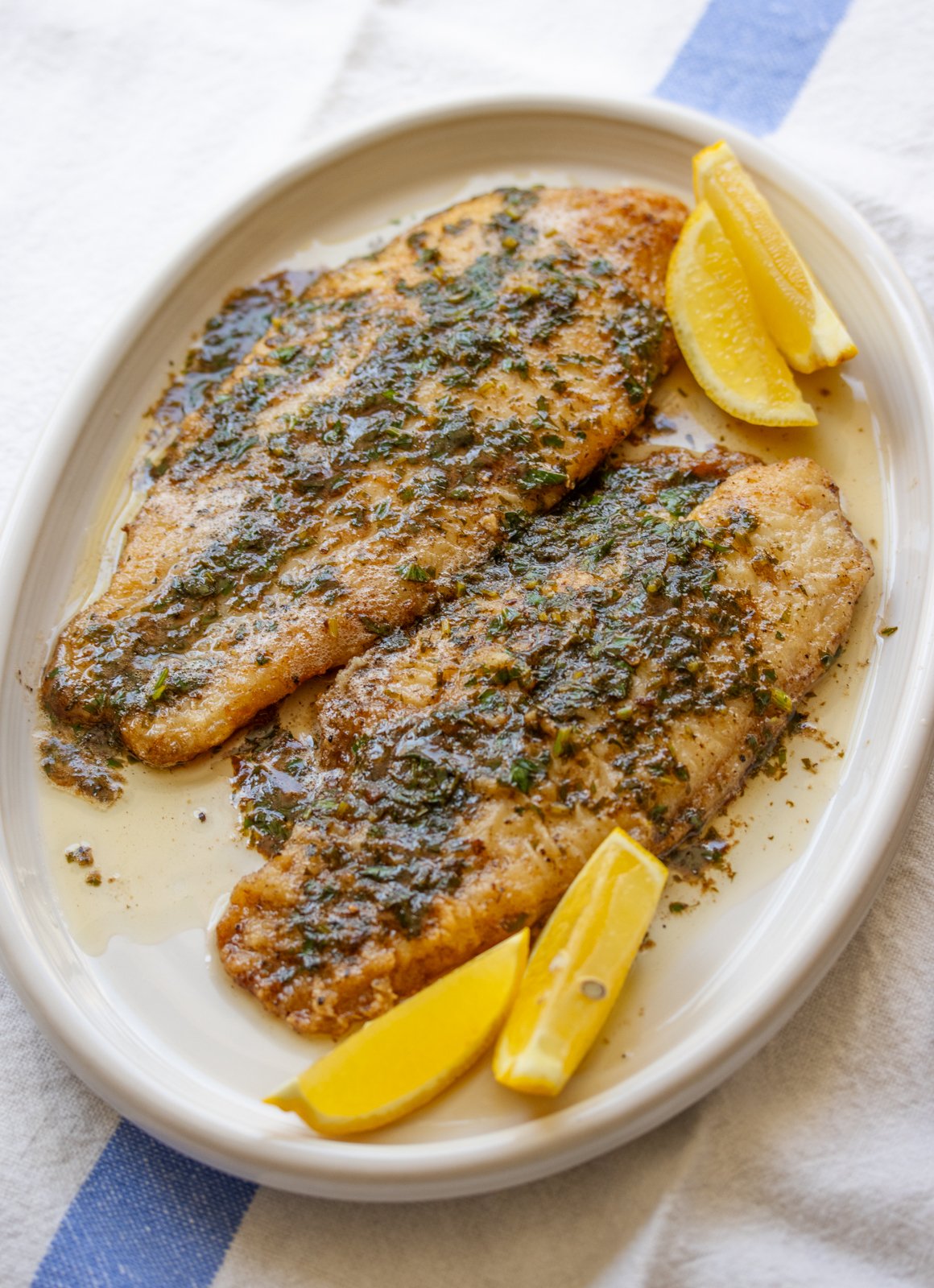 Sole meuniere on a white dish with lemon wedges