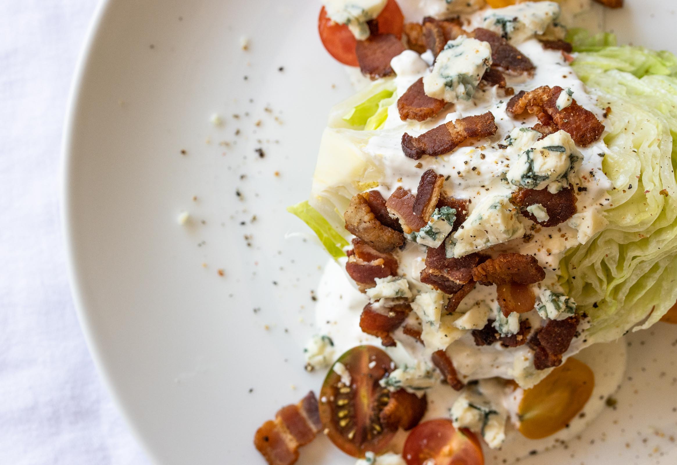 iceberg salad wedge with blue cheese dressing on a white serving plate
