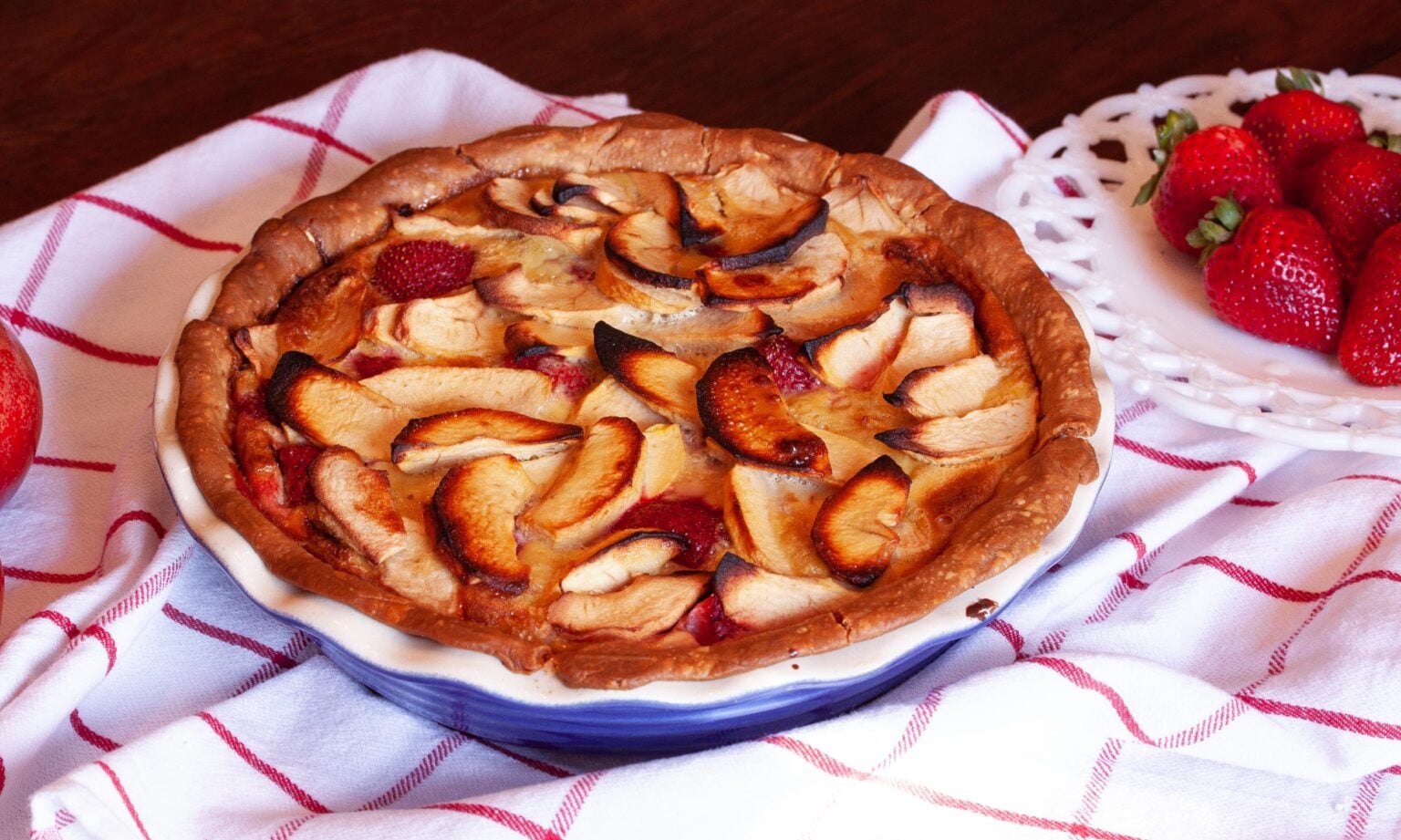 The finished pie on a white towel with strawberries next to it. 