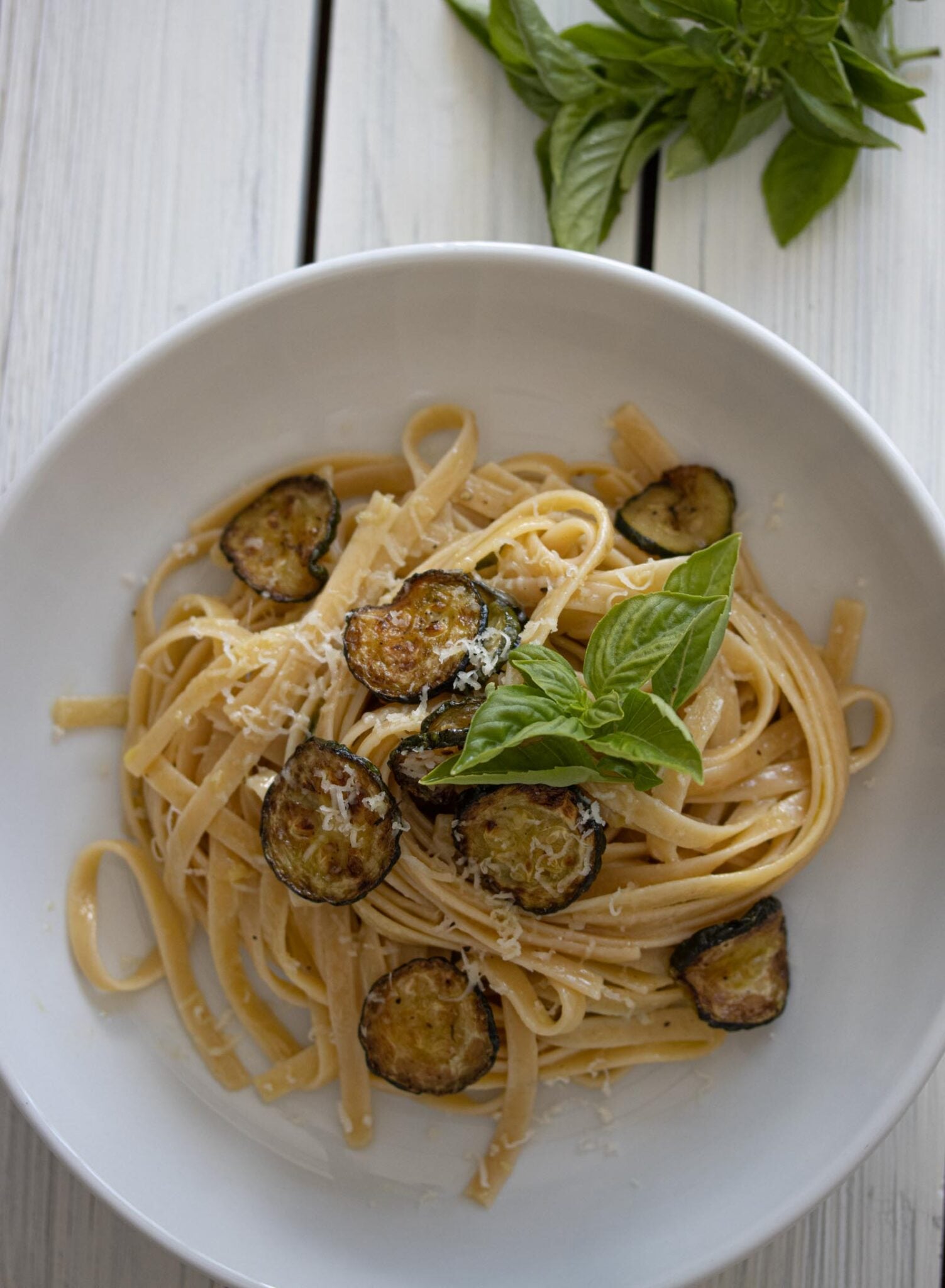 zucchini with pasta and provolone cheese in a white dish