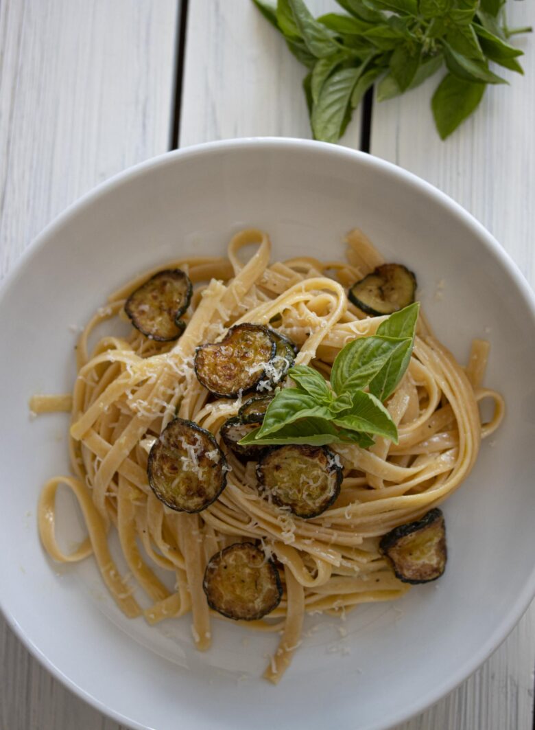 zucchini with pasta and provolone cheese in a white dish