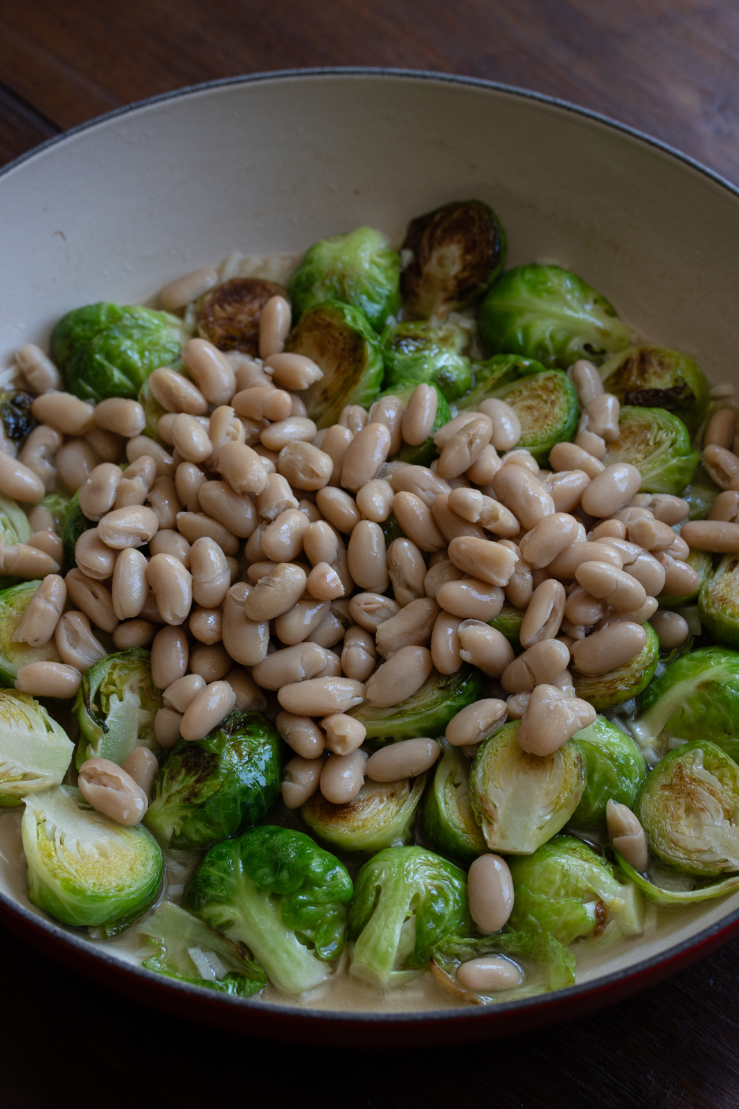 adding white beans to the brussels sprouts