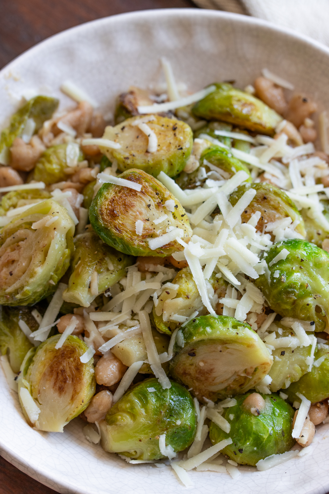 brussels sprouts and white beans in a cream color serving dish