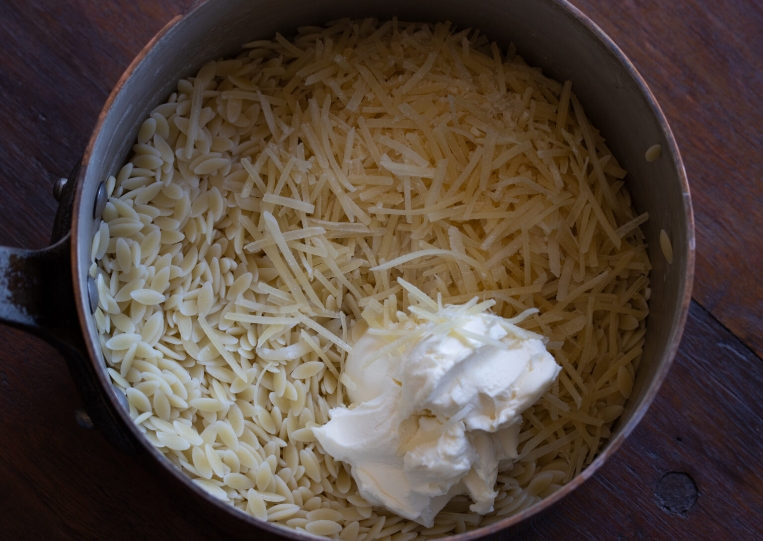 Cooked orzo pasta placed back into the cooking pan and mascarpone added