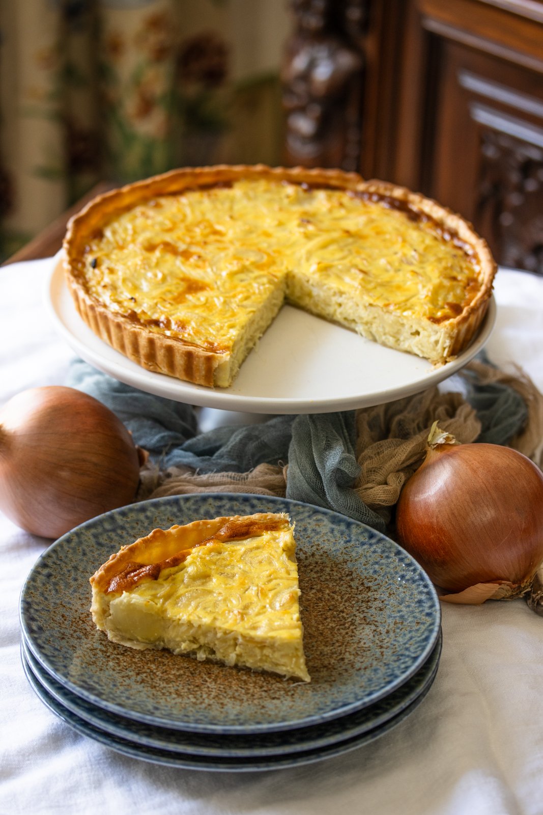The finished onion tart recipe served on a white stand. 