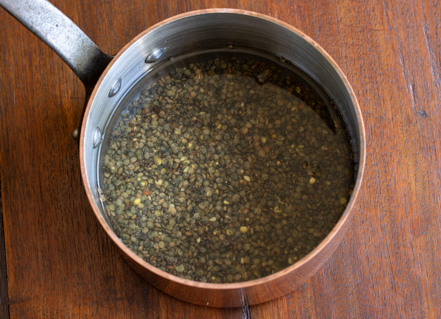 Lentils cooking in a small pan.