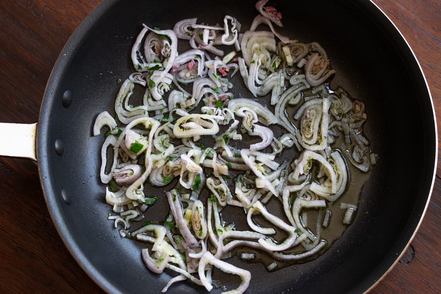 Shallots getting golden on a large skillet.