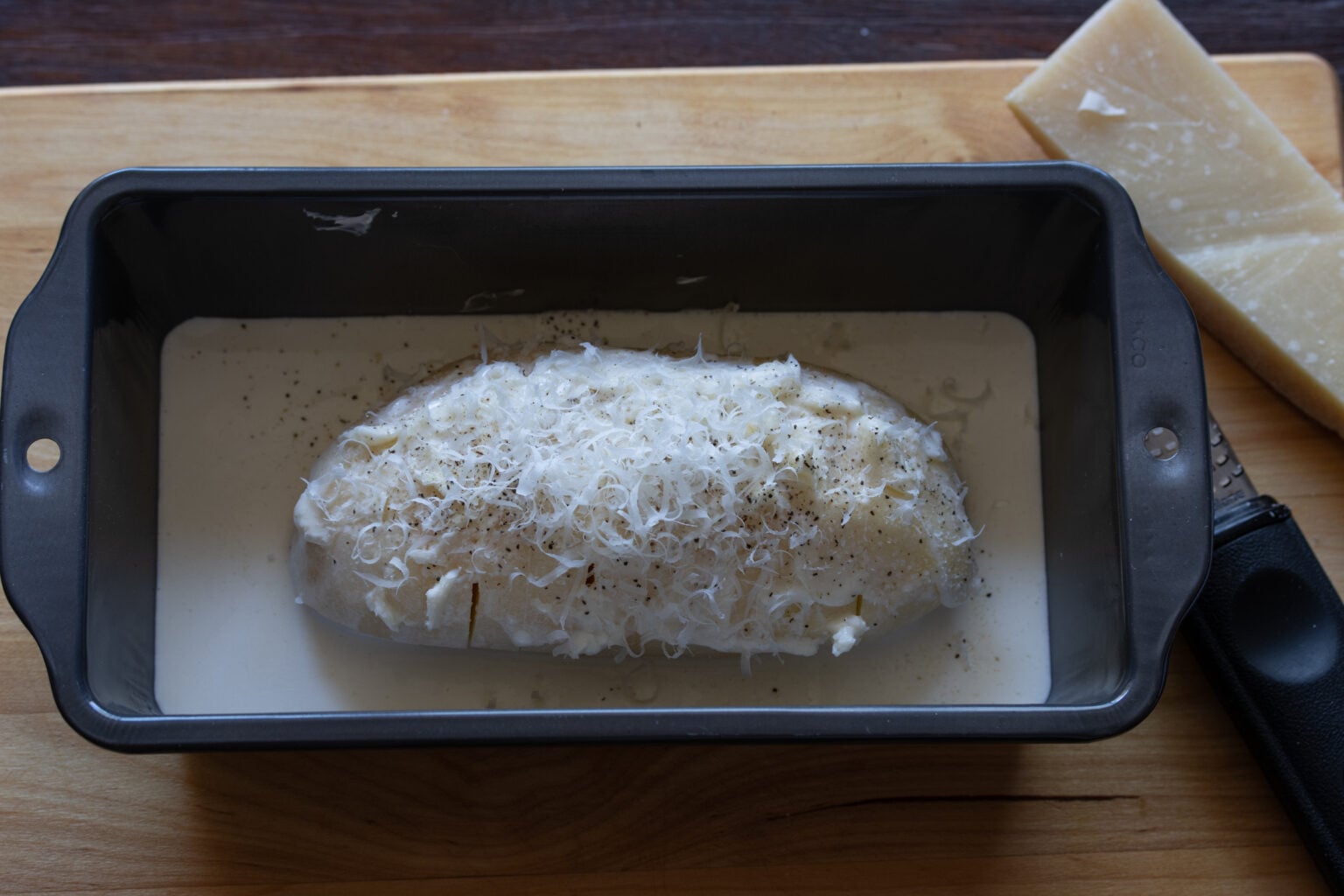 raw potatoes covered with butter in a loaf tin