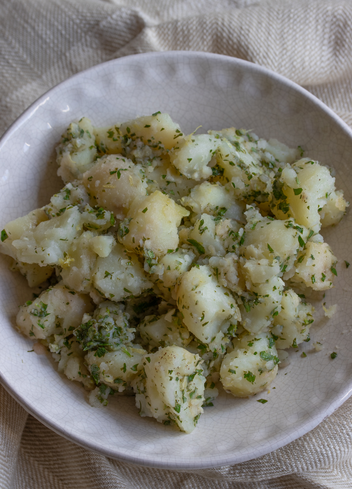 warm potato salad in a white serving bowl