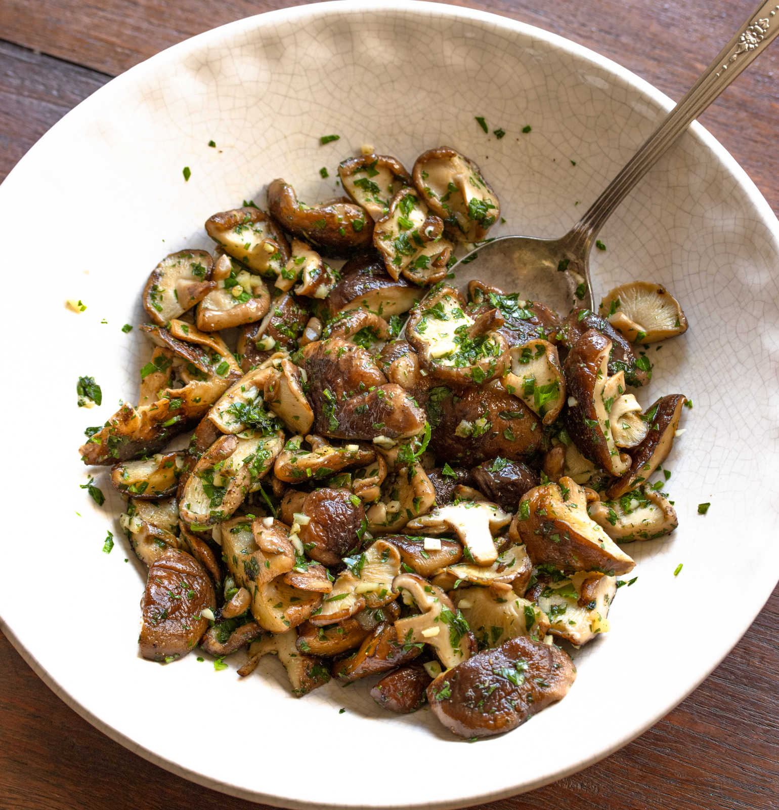 garlic mushrooms in a white erving dish with spoon