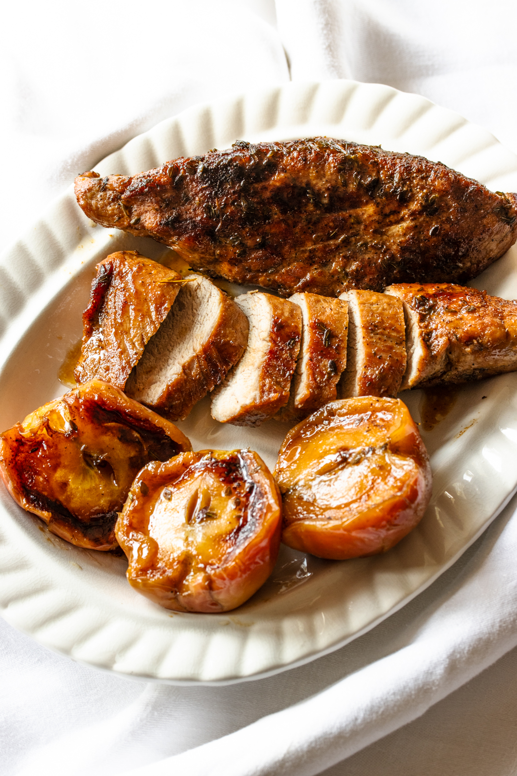 The finished pork tenderloin with apples recipe is served on a white platter.