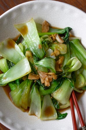 bok choy stir fry served in a white bowl with red chop sticks
