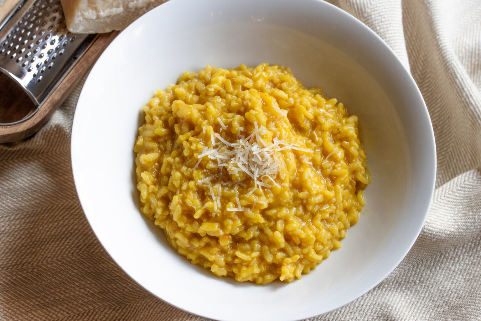 risotto done and in a white serving plate with grated cheese over it