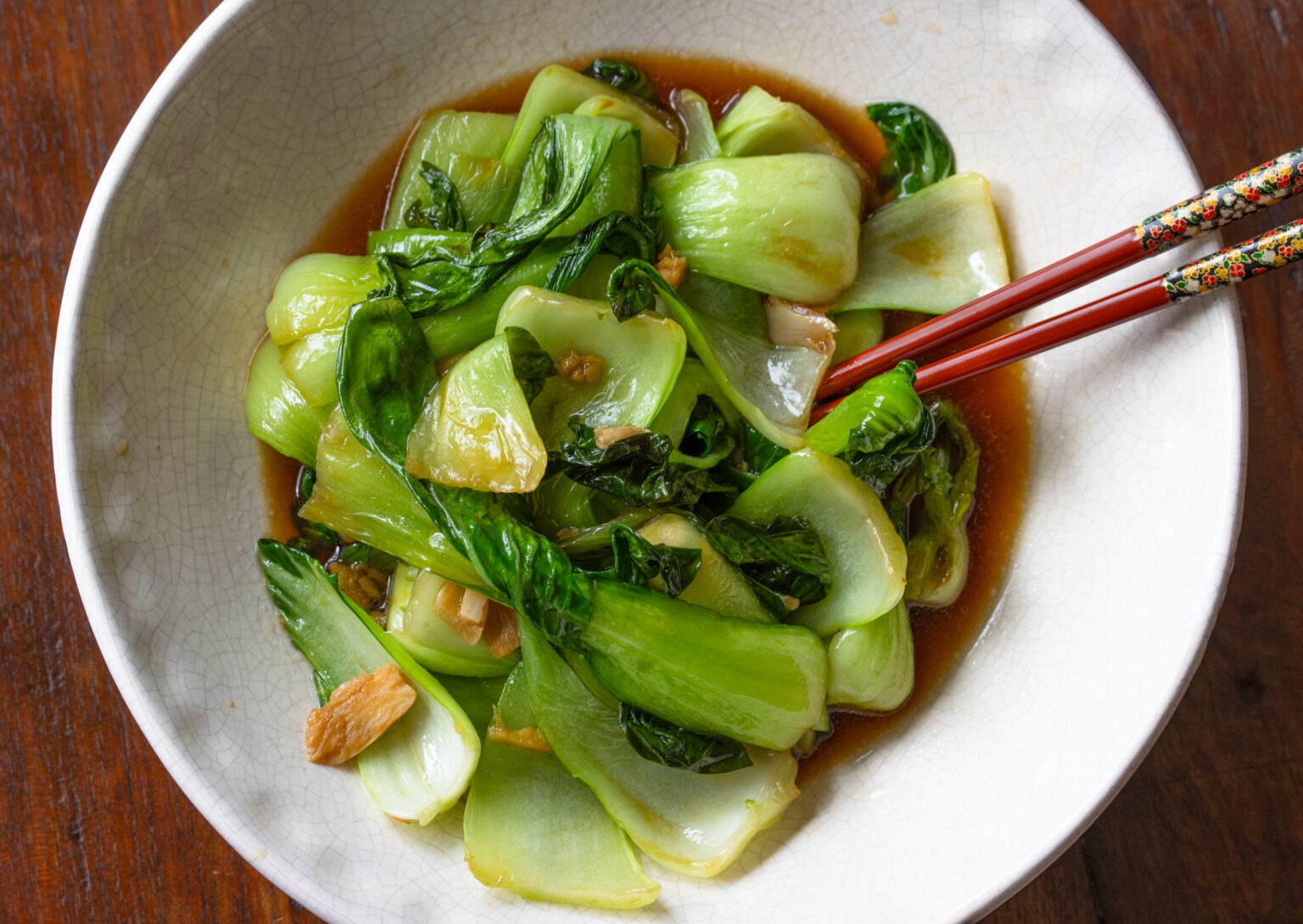 bok choy stir fry served in a white bowl with red chop sticks