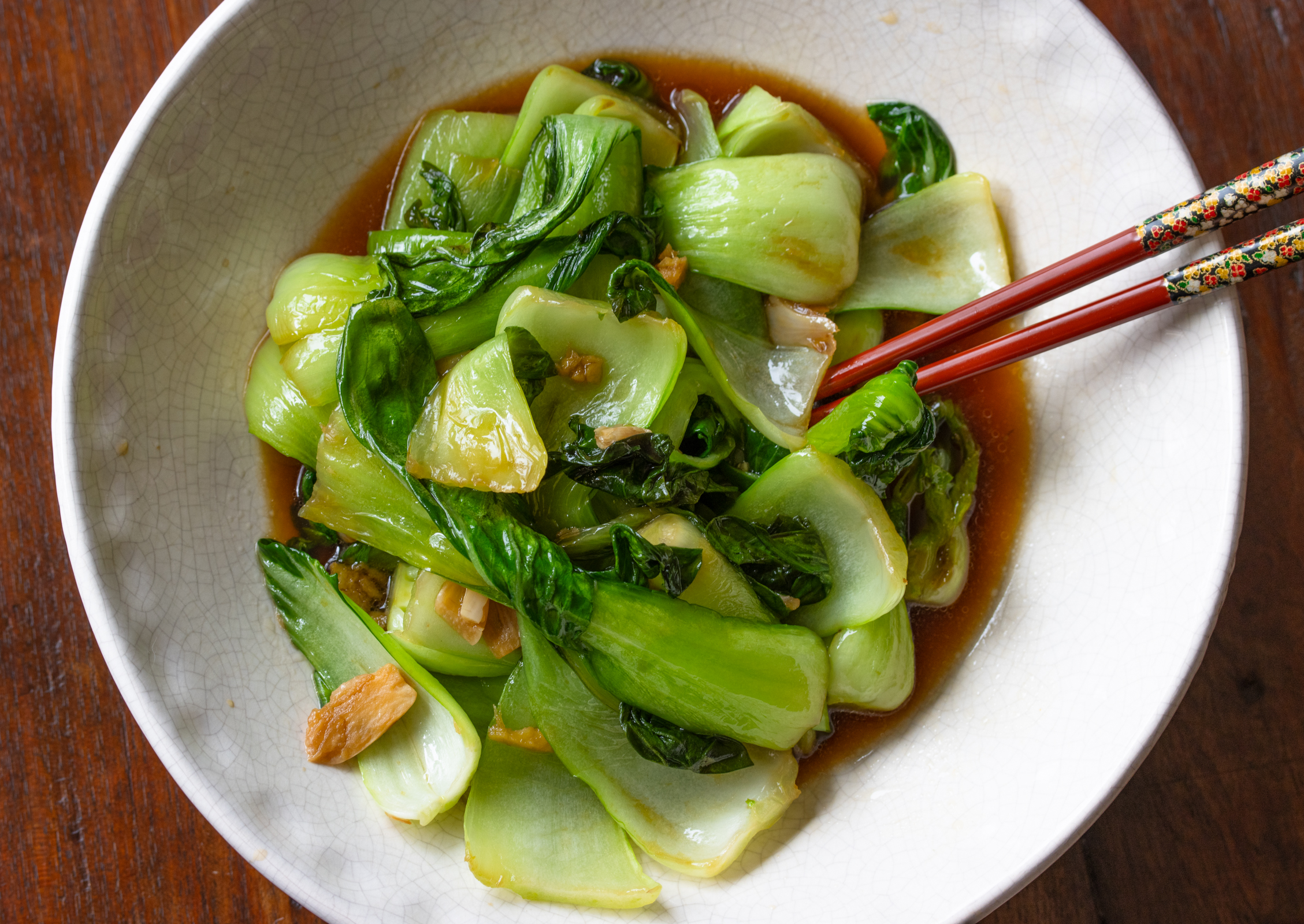 bok choy stir fry served in a white bowl with red chop sticks