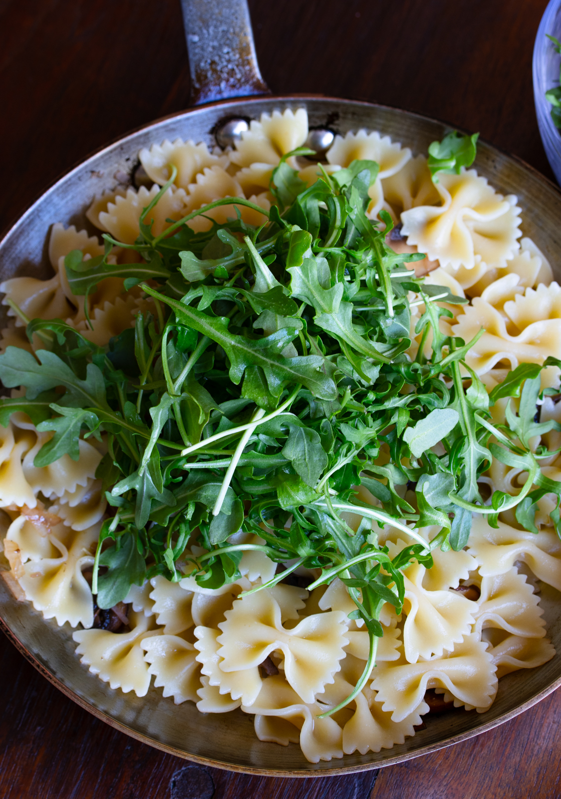 arugula added to the pasta in the skillet