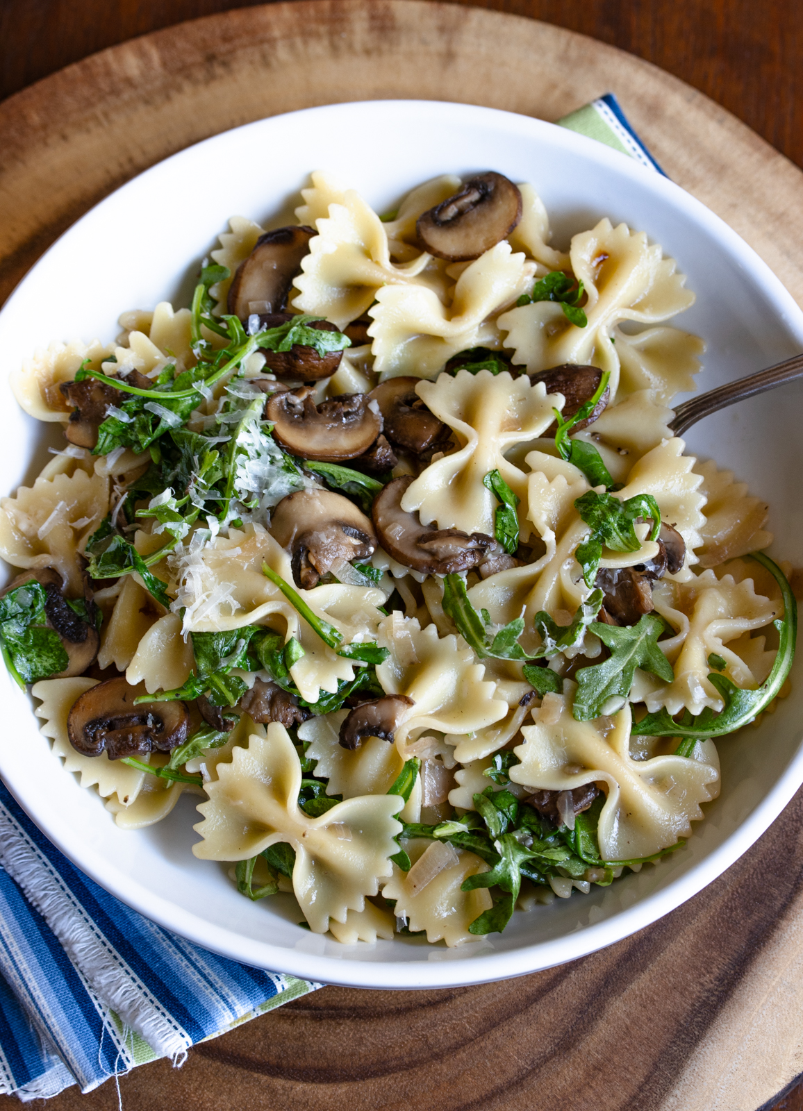 creamy mushroom pasta served in a white bowl sitting on a wood board