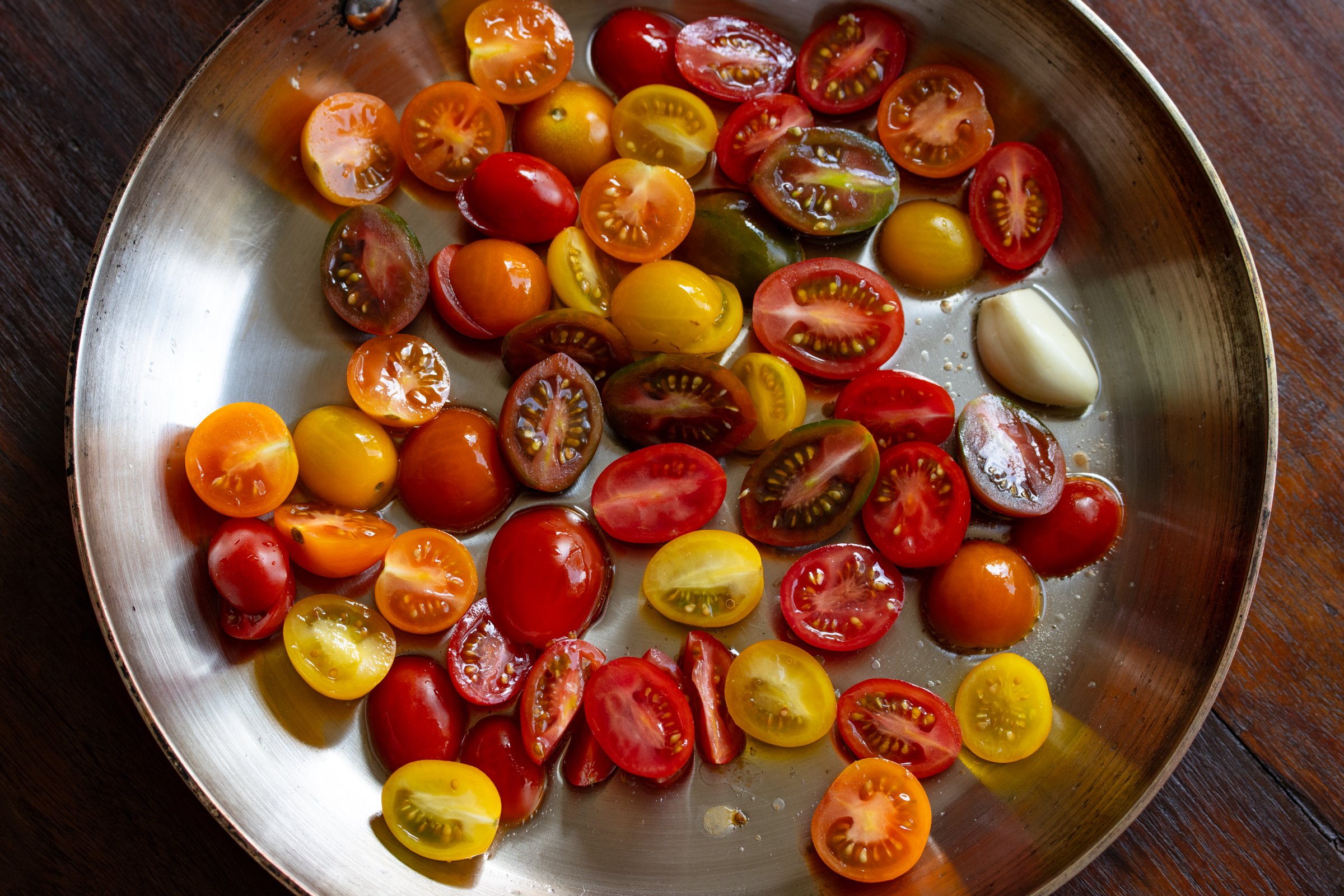 sliced tomatoes in a skillet with garlic and olive oil