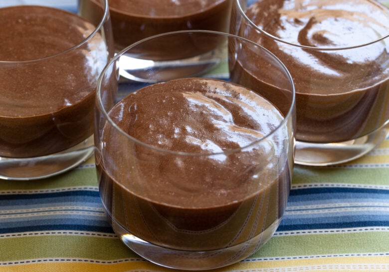 Chocolate mousse poured into glass containers ready to be refrigerated.