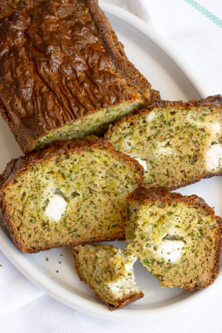 Sliced herb and feta cheese bread presented on a white serving plate.