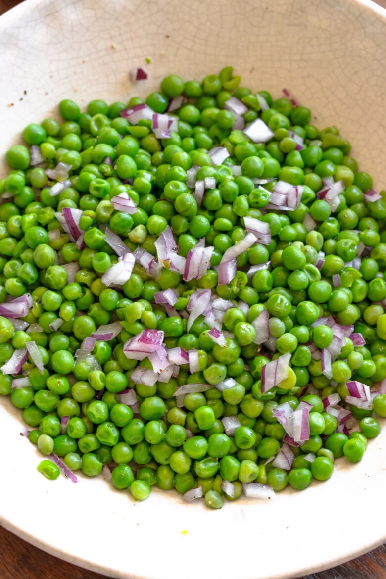 Pea salad served in a off white serving dish.