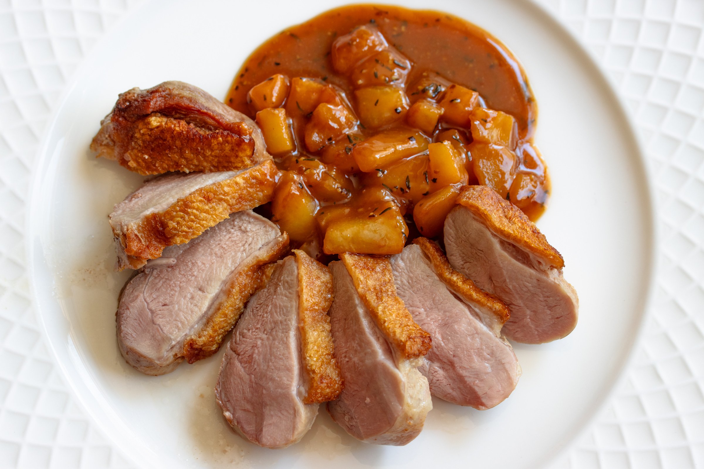 Crispy duck breasts with pear and pepper sauce.