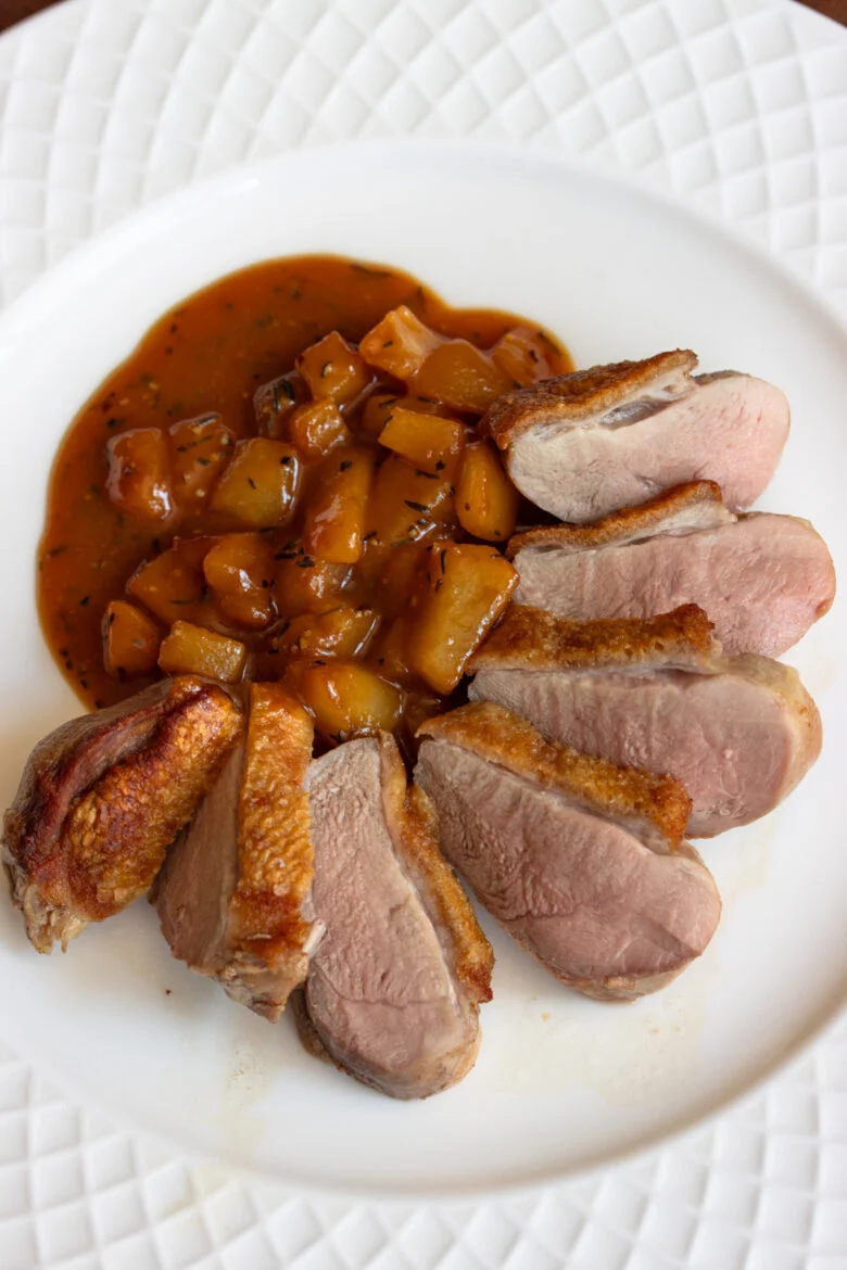 Crispy duck breasts sliced on a white plate. 