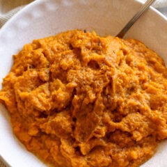 Mashed sweet potatoes ready to be enjoyed aand served in a off white serving dish.