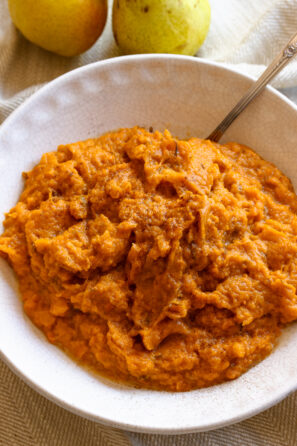 Mashed sweet potatoes ready to be enjoyed aand served in a off white serving dish.