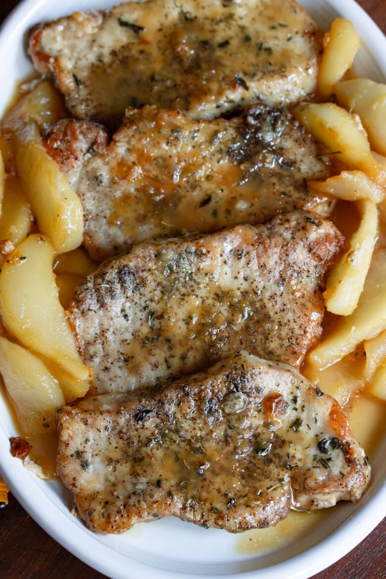 Pan-fried boneless pork chops served with pears in a white oval plate.