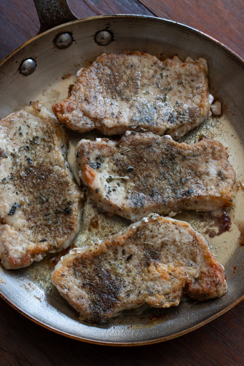 Boneless pork chops in the skillet getting golden color.