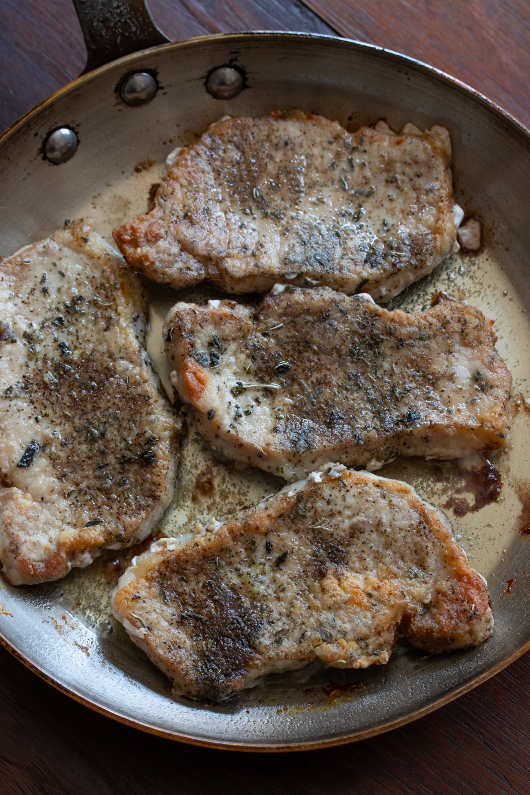 Boneless pork chops in the skillet getting golden color. 