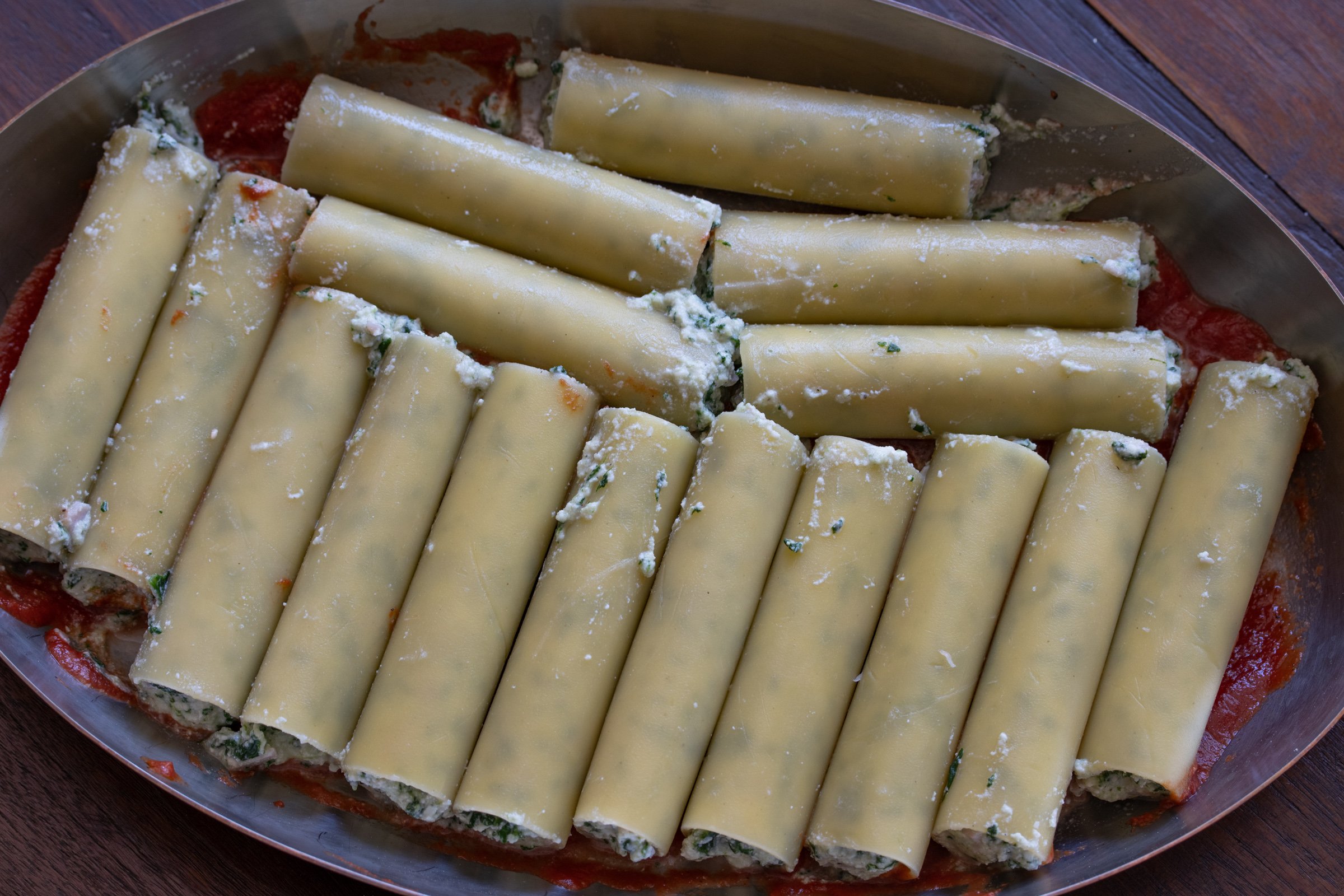 Stuffed cannelloni placed in an oval baking dish.