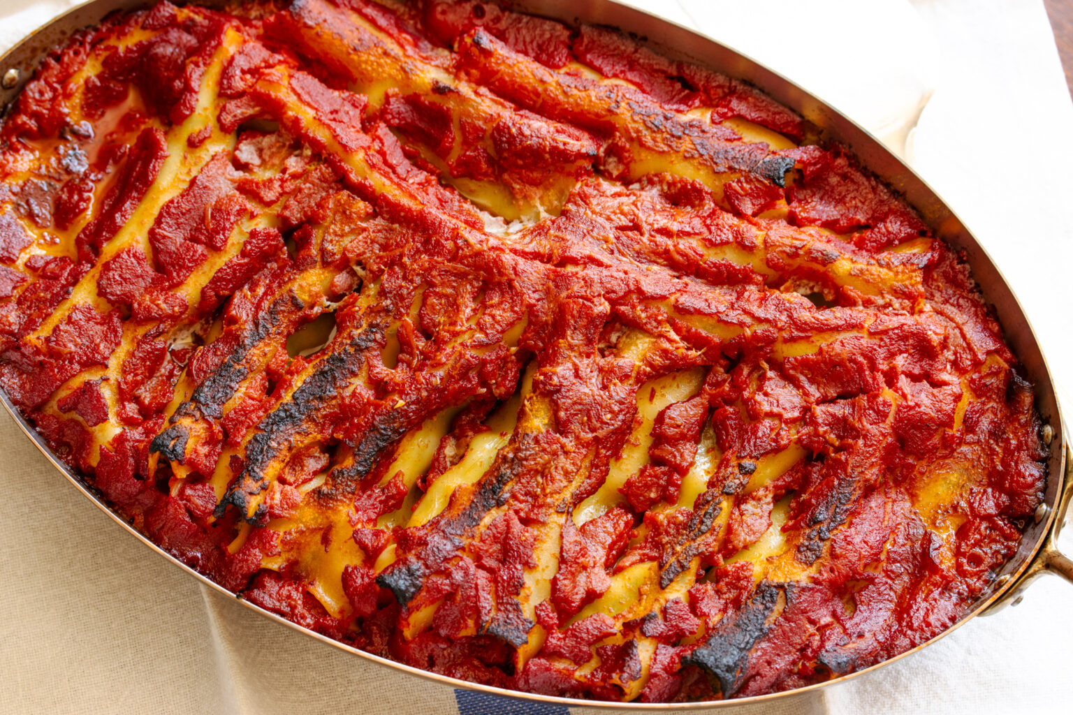 Cannelloni out of the oven in an oval baking dish.
